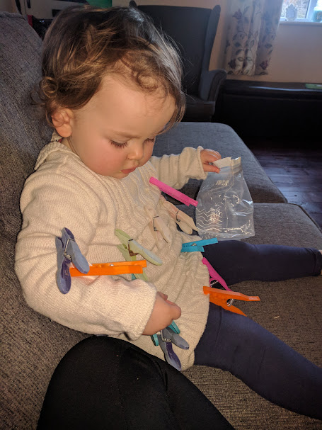 Young child exploring clothes pegs during fine motor play at home